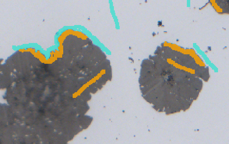 Close-up of gray circular fragments on pale background with orange and cyan annotation strokes